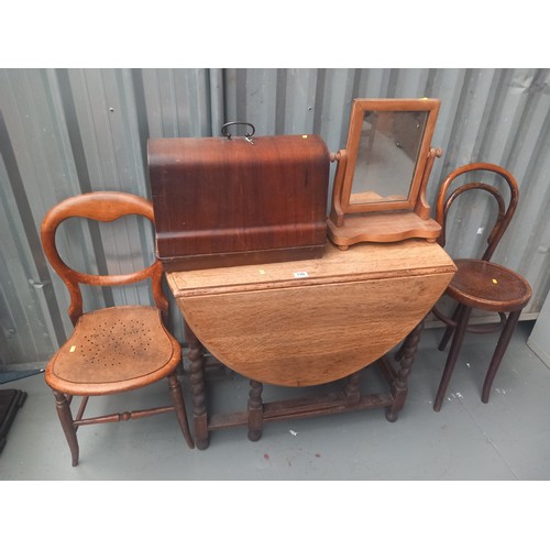 139 - An oak drop leaf dining table, two chairs, sewing macine and a dressing table mirror