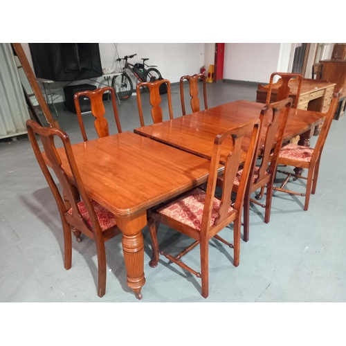 569 - A mahogany wind out dining table with two extra leaves and hand crank together with eight chairs