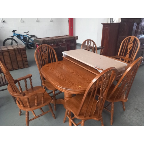 127 - An oak extending dining table with two extra leaves together with six wheelback dining chairs