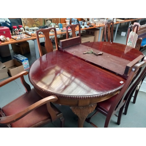 105 - An extending mahogany wind out dining table with hand crank and two extra leaves together with seven... 