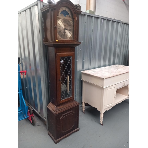 134 - An oak cased grandfather clock with weights, pendulum and keys