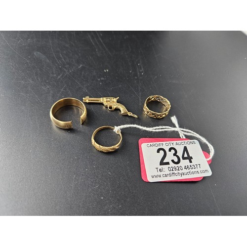 234 - A 9k gold gun charm, two rings and a scrap ring - combined gold weight is 15.2 grams