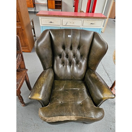 125 - A green leather Chesterfield style wingback armchair