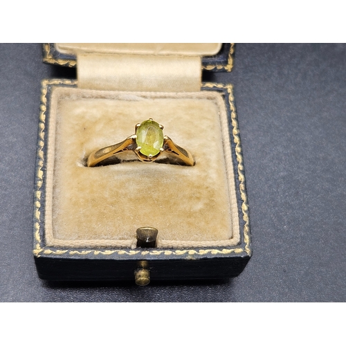 565 - An 18k gold ladies dress ring with pale green stone - weight including stone is 2.6 grams