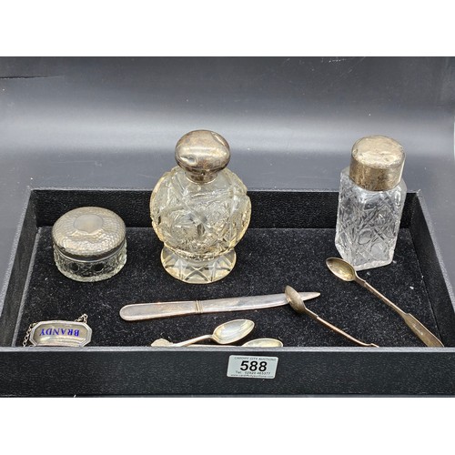 588 - Three silver topped dressing table bottles, silver sugar tongs, two teaspoons and a decanter label a... 