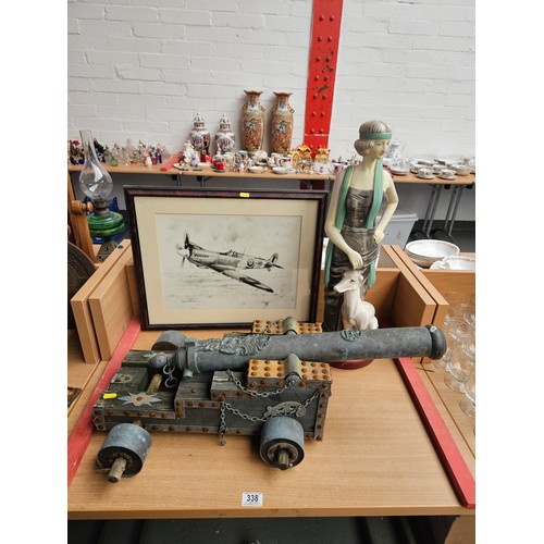 338 - An Art Deco style figurine, a metal and wood canon and a framed picture of a Spitfire