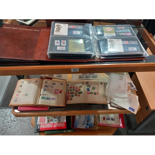 524 - Stamp albums, presentation packs and first day covers displayed over two shelves