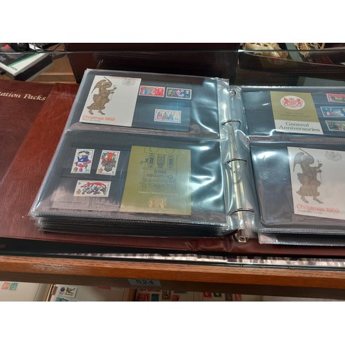 524 - Stamp albums, presentation packs and first day covers displayed over two shelves