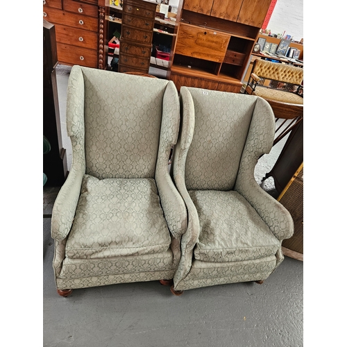 414 - A pair of wingback upholstered armchairs on castors