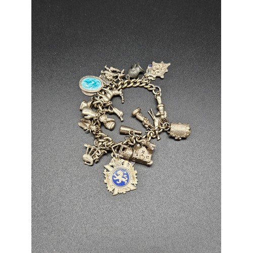 503 - A silver charm bracelet with charms - many being silver - total weight 86.5 grams