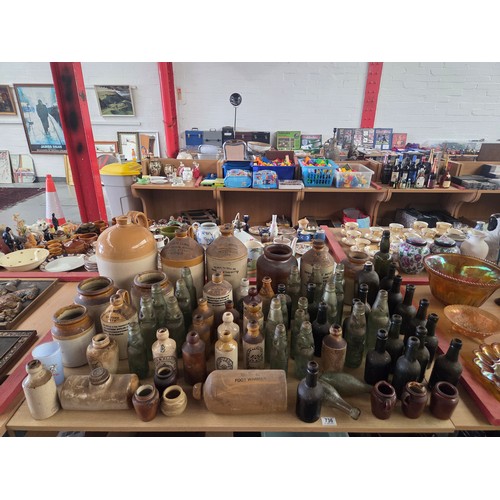 736 - A collection of stoneware flagans with a quantity of glass bottles marked Cardiff, Leicester, Chepst... 
