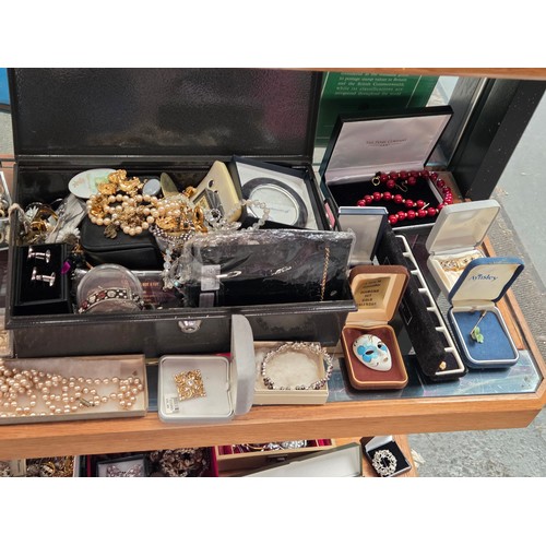 932 - A quantity of costume jewellery displayed over three shelves
