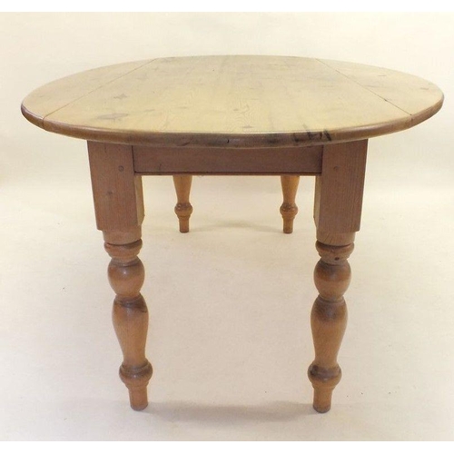 1174 - A long oval pine dropleaf kitchen table on turned supports