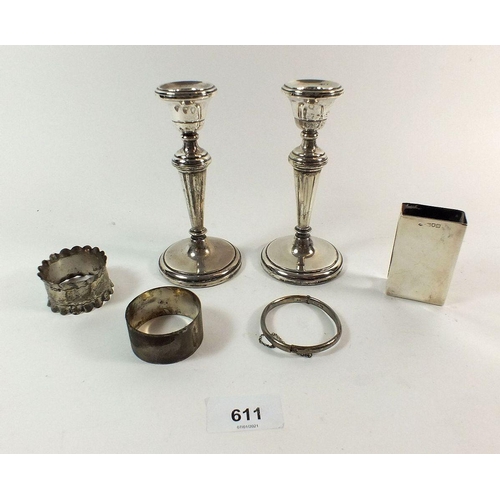 611 - A pair of silver candlesticks, a matchbox cover and two napkin rings - weighable silver 76g