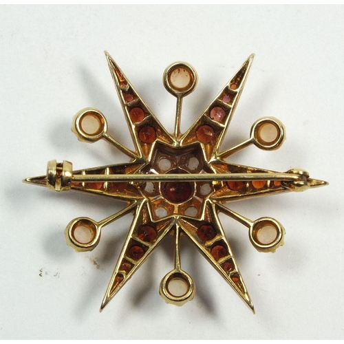 674 - A 9 carat gold garnet and pearl star form brooch, 7.5g, 3.8cm diameter