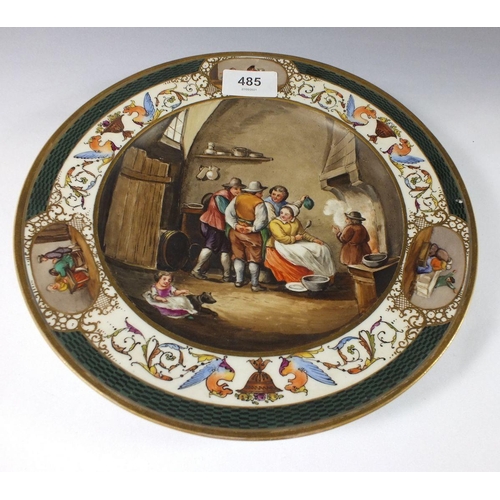 485 - A Vienna style dish painted interior scene with figures around a hearth, 24.5cm diameter