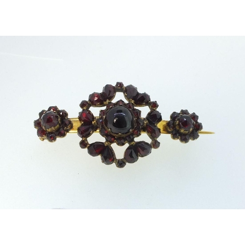 772 - A Victorian yellow metal brooch set three garnet clusters