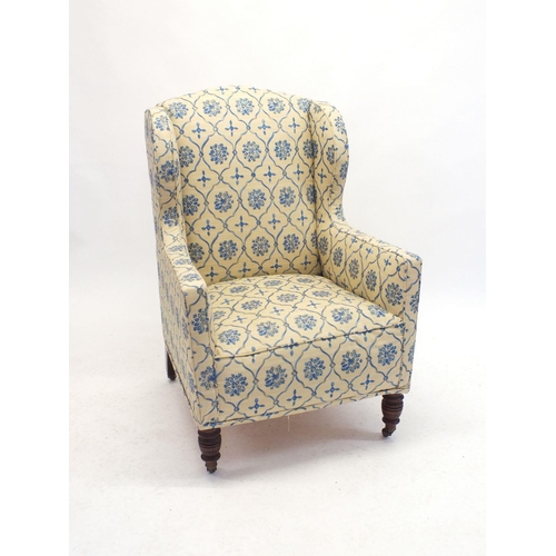 1019 - An Edwardian wing armchair upholstered in blue and yellow floral fabric, all on turned supports