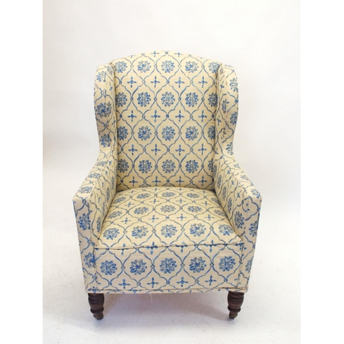 1019 - An Edwardian wing armchair upholstered in blue and yellow floral fabric, all on turned supports