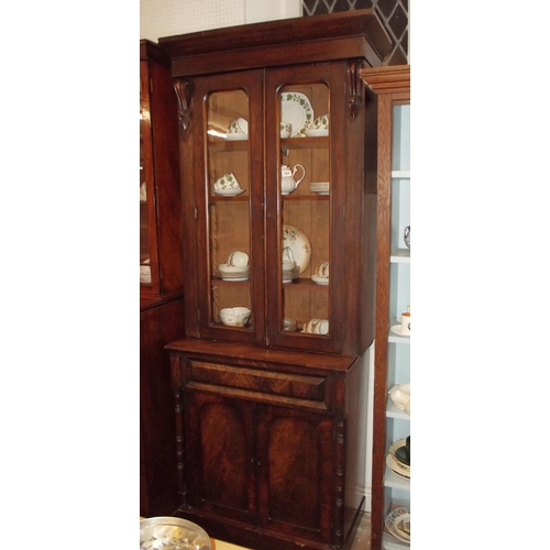 1024 - A Victorian mahogany bookcase of small proportions with two glazed doors over drawer and cupboard