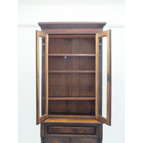 1024 - A Victorian mahogany bookcase of small proportions with two glazed doors over drawer and cupboard