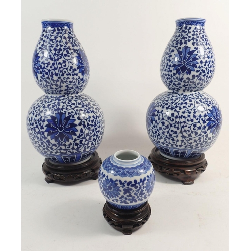 109 - A pair of Chinese blue and white double gourd form vases on stands, 23cm and a smaller one