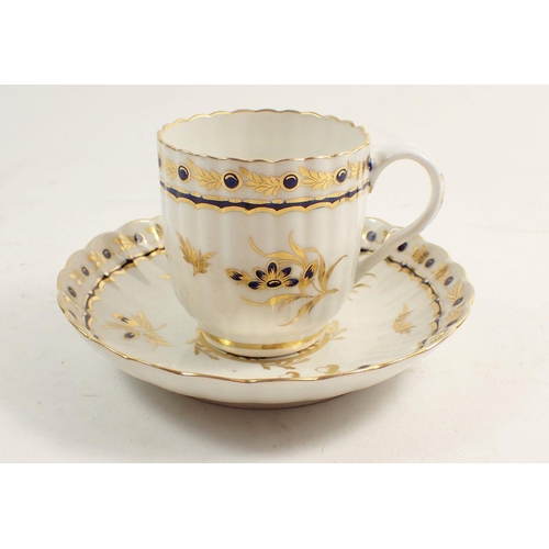 131 - An 18th century Worcester tea cup and saucer,  painted blue and gilt sprays with blue crescent mark