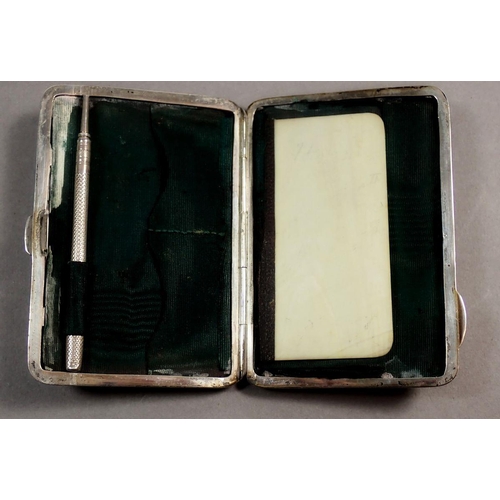 237 - An Edwardian silver note case with scroll decoration and fitted interior containing a pencil and ivo... 