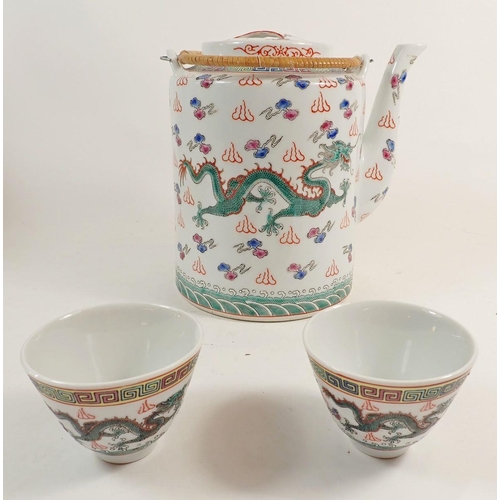 83 - A Chinese porcelain teapot and two tea bowls, painted dragons, in wicker basket