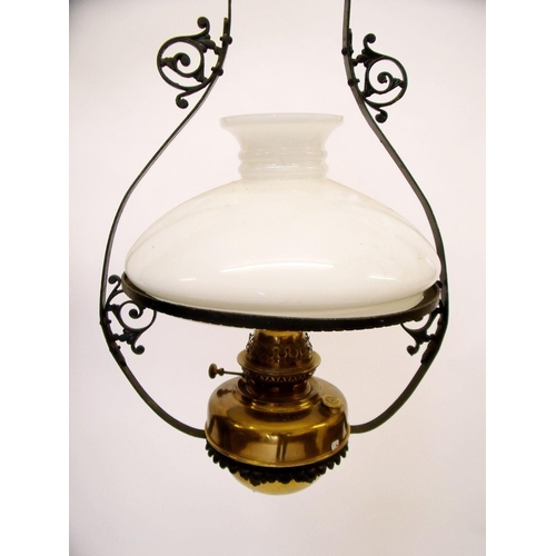 938 - A brass hanging oil lamp with glass shade and wrought iron hanger