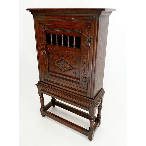 1275 - An antique oak ecclestical cupboard with spindle panel and carved door, all on turned stand, 67 x 24... 