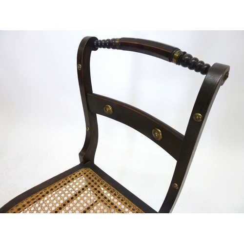 1292 - An early 19th century ebonised and cane seated chair with brass stud decoration