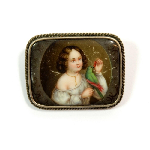 667 - A porcelain brooch painted girl with exotic bird