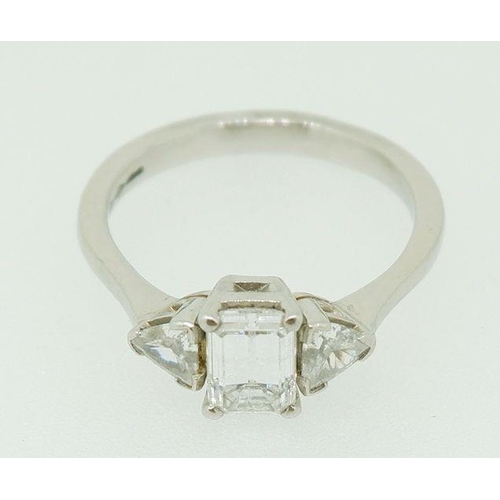 243 - A fine platinum ring set central emerald cut diamond flanked by two trilliant cut diamonds, size N, ... 