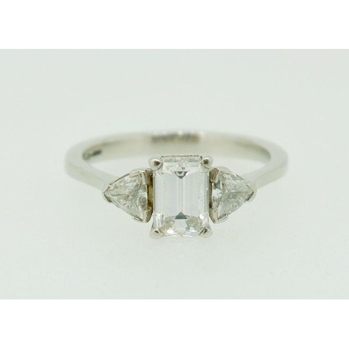 243 - A fine platinum ring set central emerald cut diamond flanked by two trilliant cut diamonds, size N, ... 