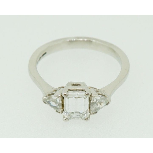 243 - A fine platinum ring set central emerald cut diamond flanked by two trilliant cut diamonds, size N, ... 