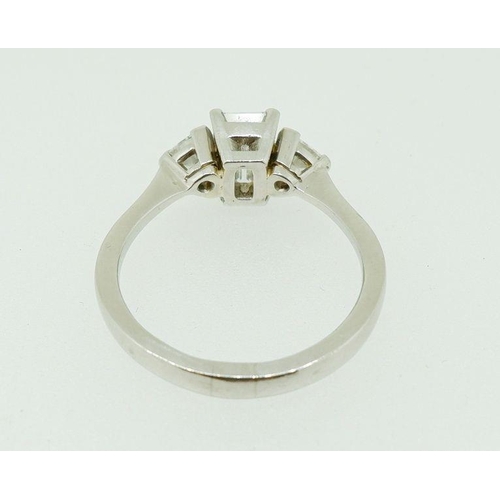 243 - A fine platinum ring set central emerald cut diamond flanked by two trilliant cut diamonds, size N, ... 