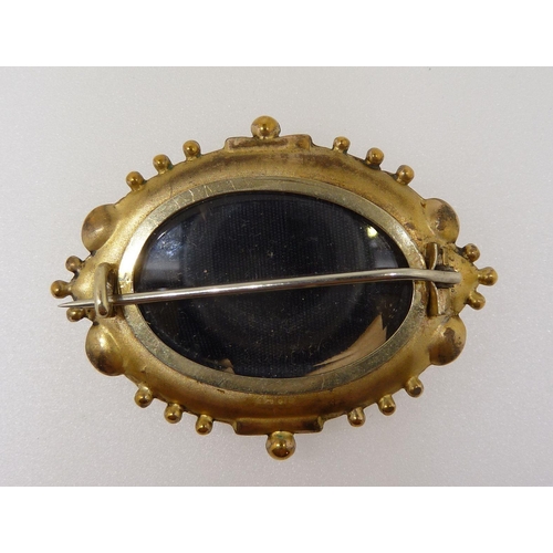 296 - A Victorian yellow metal fronted oval brooch with embossed decoration and set chip diamond