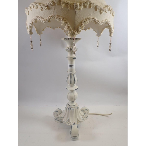 1207 - A white painted table lamp on scrollwork base, 79cm tall