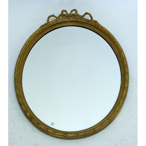 1216 - An oval gilt framed mirror with ribbon surmount