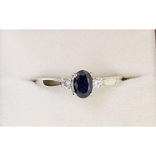 438 - A 9 carat white gold ring set oval cut sapphire flanked by two diamonds, 2.1g, size R