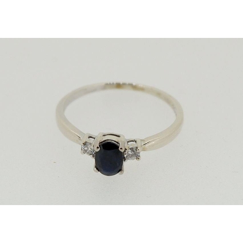 438 - A 9 carat white gold ring set oval cut sapphire flanked by two diamonds, 2.1g, size R