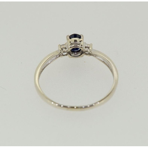 438 - A 9 carat white gold ring set oval cut sapphire flanked by two diamonds, 2.1g, size R