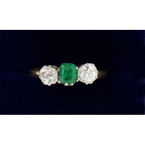 446 - A 18 carat gold ring set emerald flanked by two diamonds (each .4cts each), size O