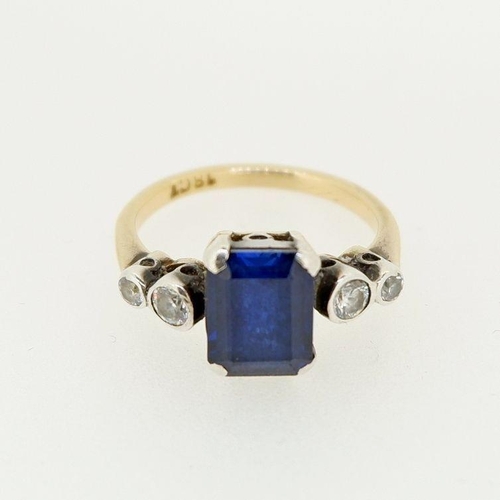 472 - An 18ct gold ring set rectangular cut sapphire flanked by four white stones, size M to N