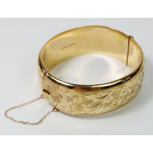 540 - A 9ct gold hinged and engraved bangle, 33gm