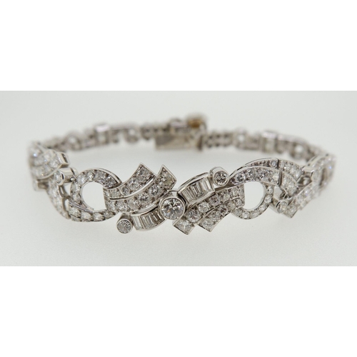 548 - A fine diamond bracelet set baguette and brilliant cut stones with scrollwork asymetrical central pa... 