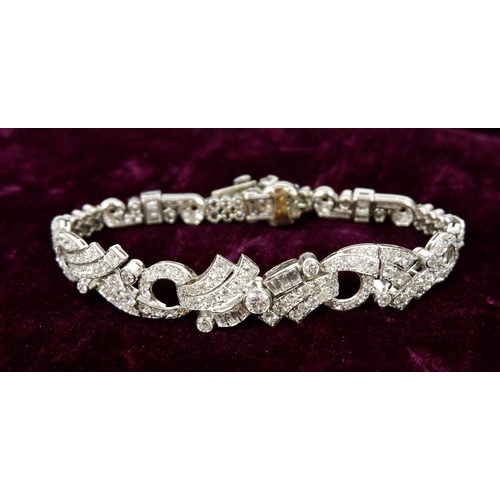 548 - A fine diamond bracelet set baguette and brilliant cut stones with scrollwork asymetrical central pa... 