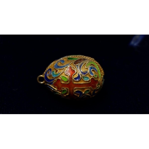 551 - A Russian style enamel miniature egg form pendant or charm with crucifix and scrollwork decoration, ... 