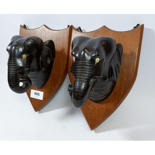 966 - A pair of shield form ebony elephant wall plaques, 24cm tall